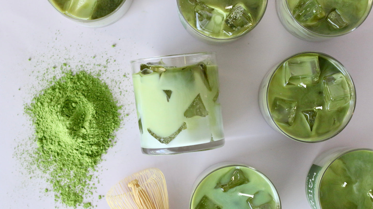 Green iced tea with matcha powder and a wooden spoon on a white surface