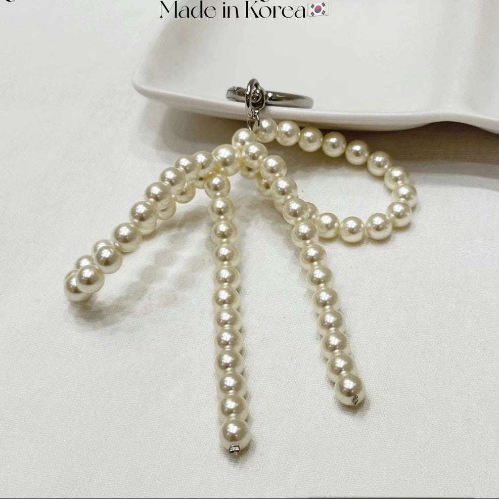 A pearl bow bag charm sitting on a vanity tray