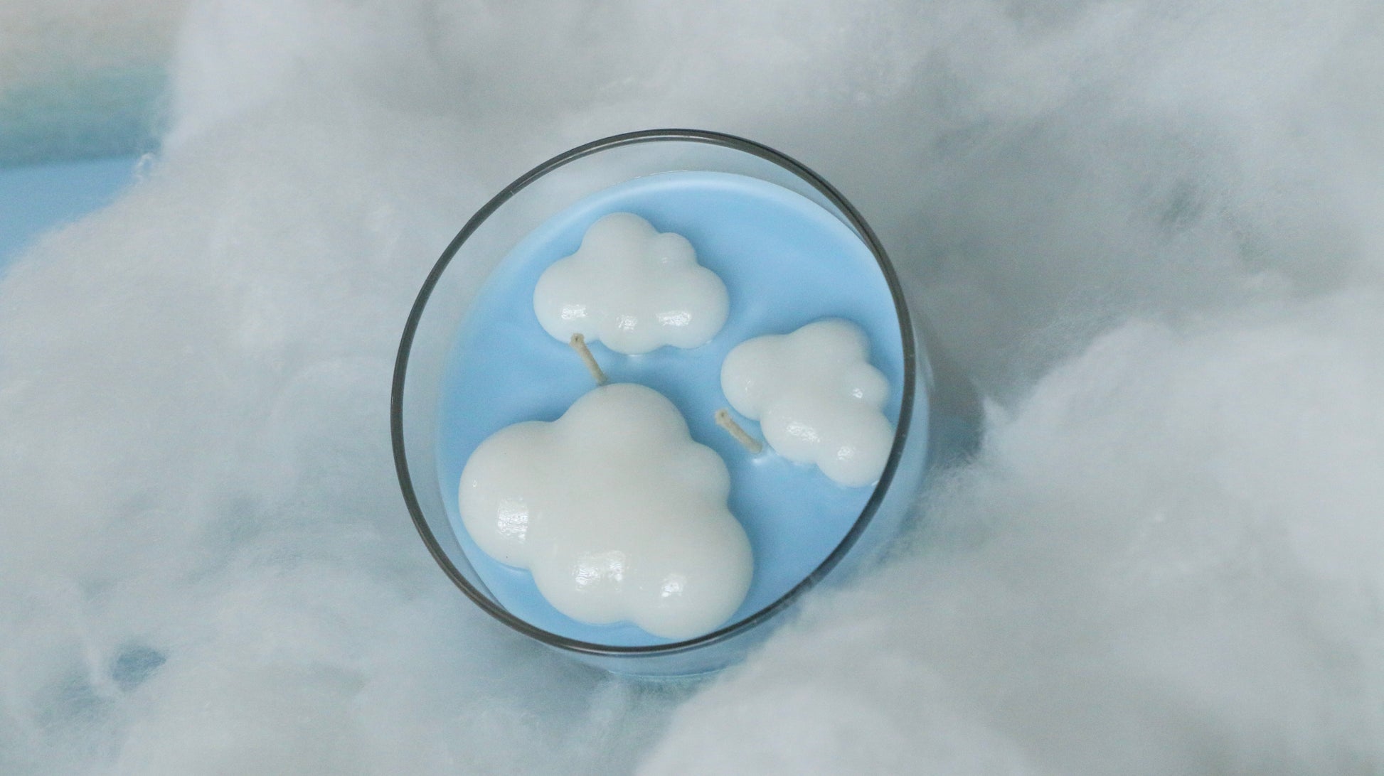 Cloud-shaped candles in a glass bowl on a snowy background