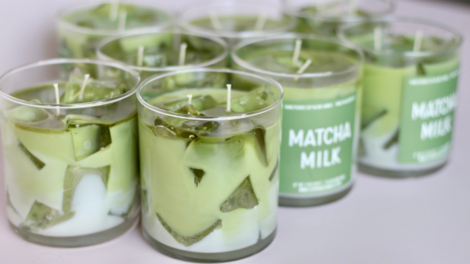 Matcha milk candles in clear containers with green labels on a white background