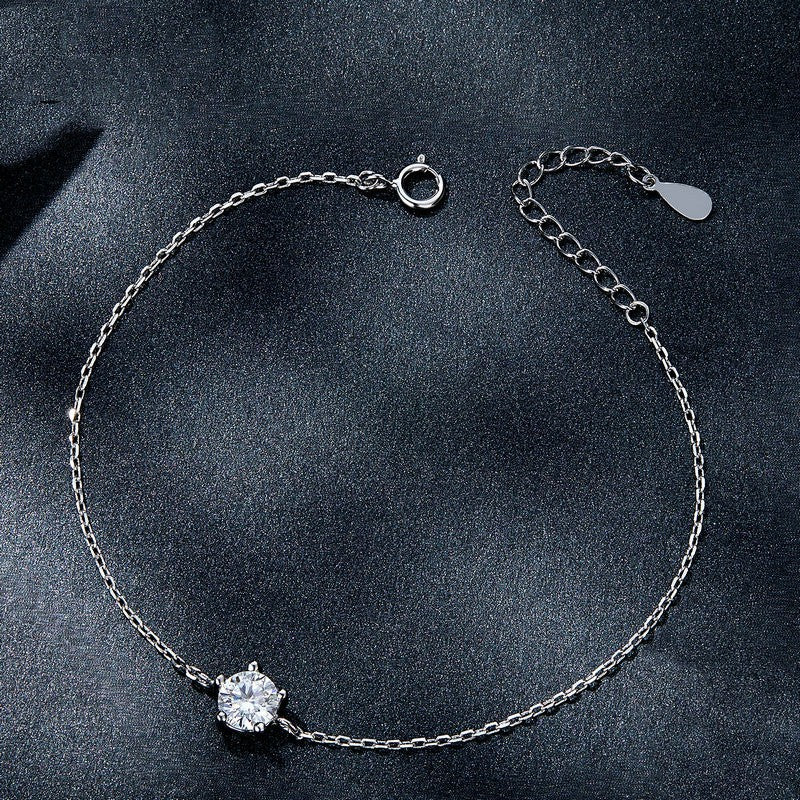 Silver bracelet with a single diamond on a dark background