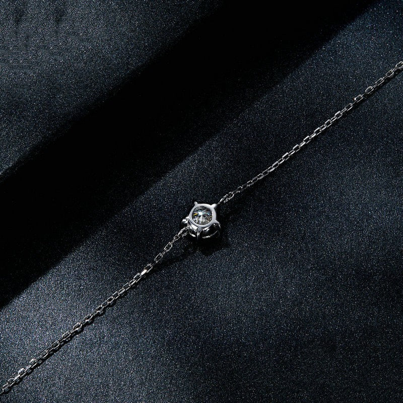 Silver bracelet with a diamond on a dark fabric background