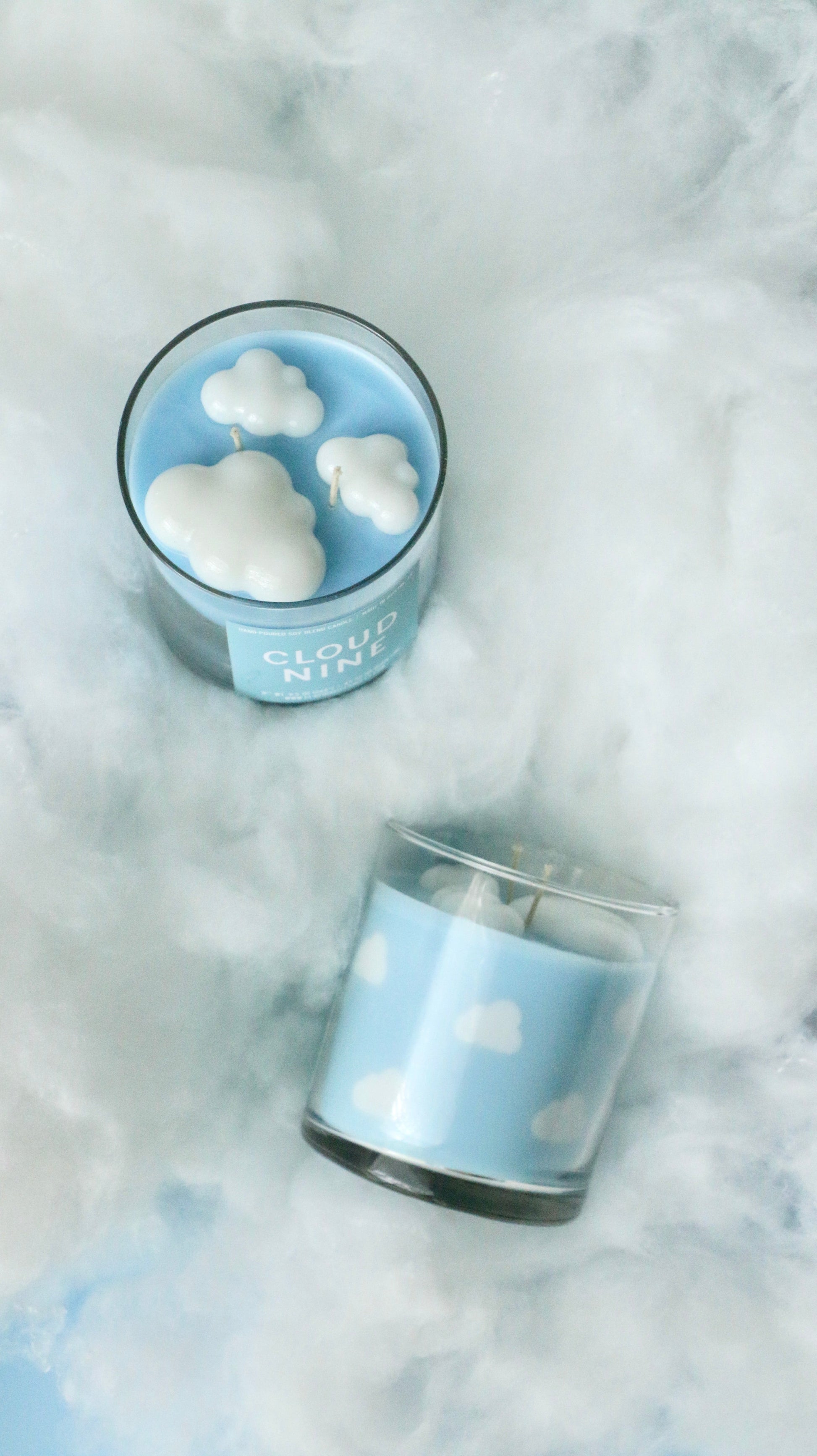 Two blue candles with cloud designs on a soft white background