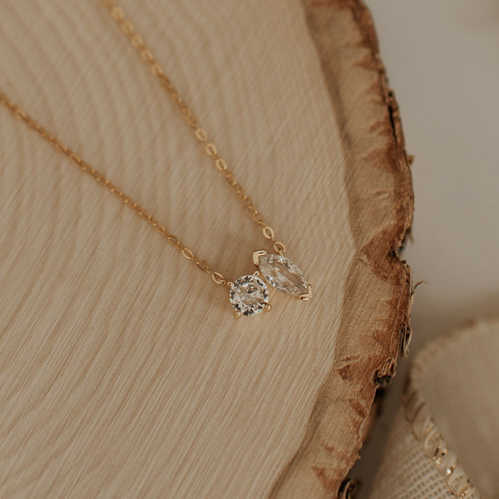Gold necklace with a diamond pendant on a wooden surface