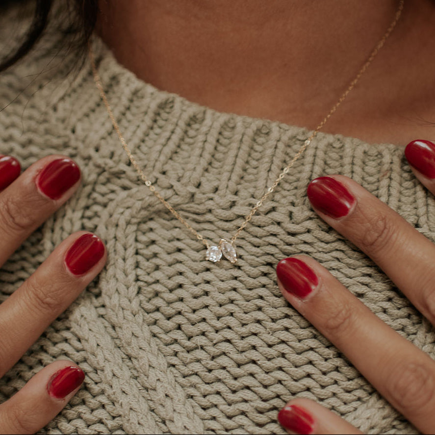 Woman wearing a necklace in an oatmeal sweater