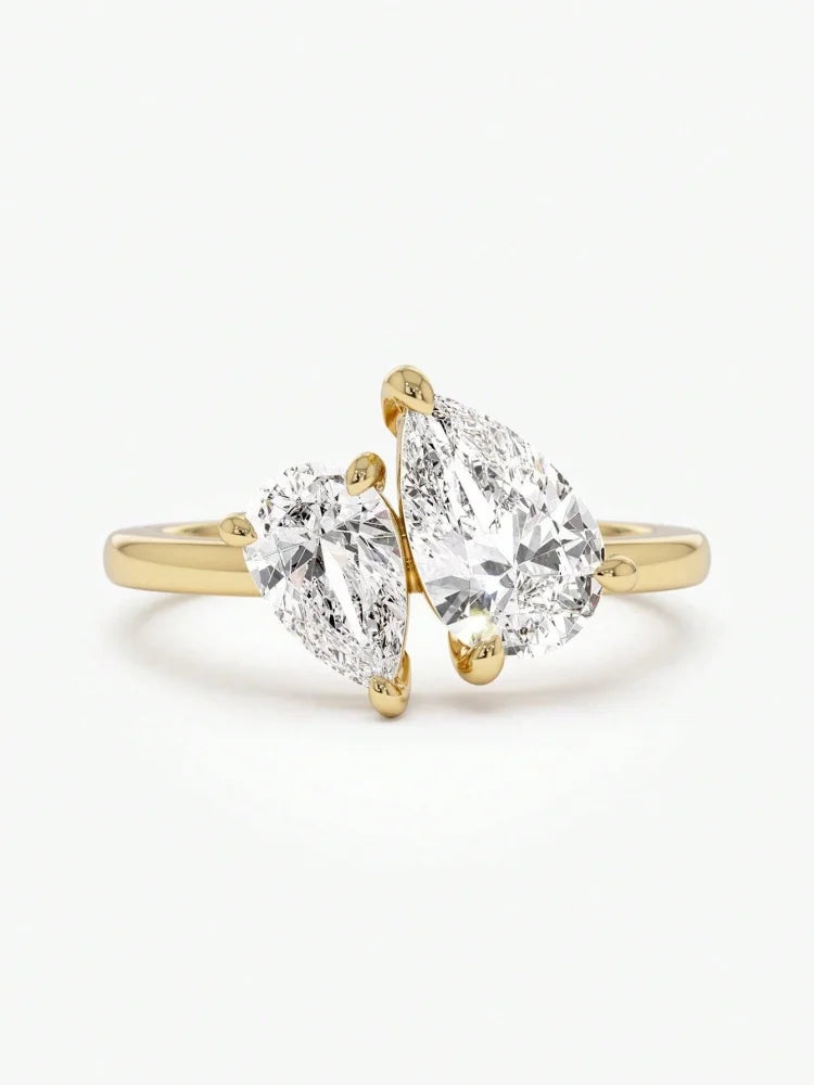 Gold ring with two pear-shaped diamonds on a white background