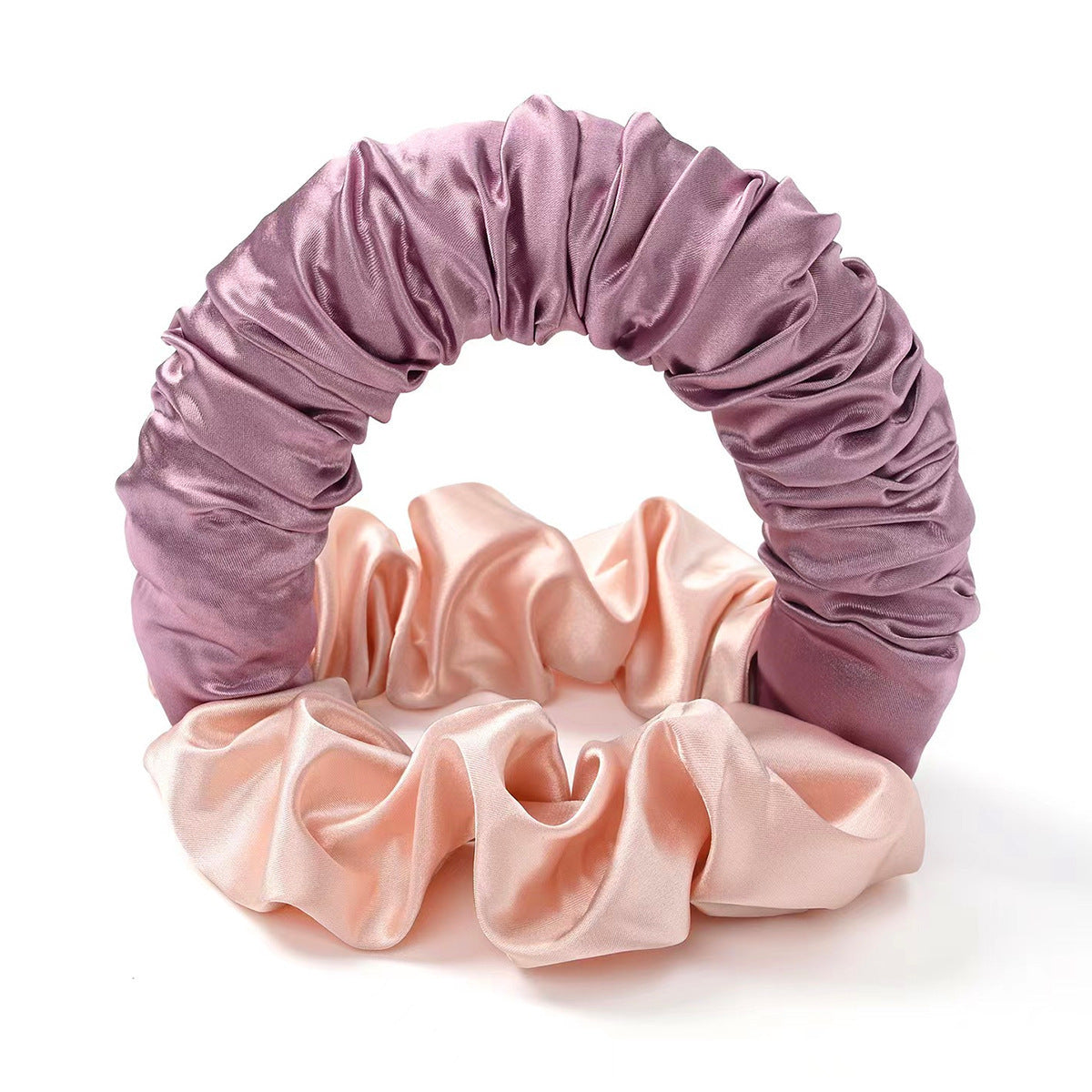 Two satin scrunchies, one pink and one purple, on a white background