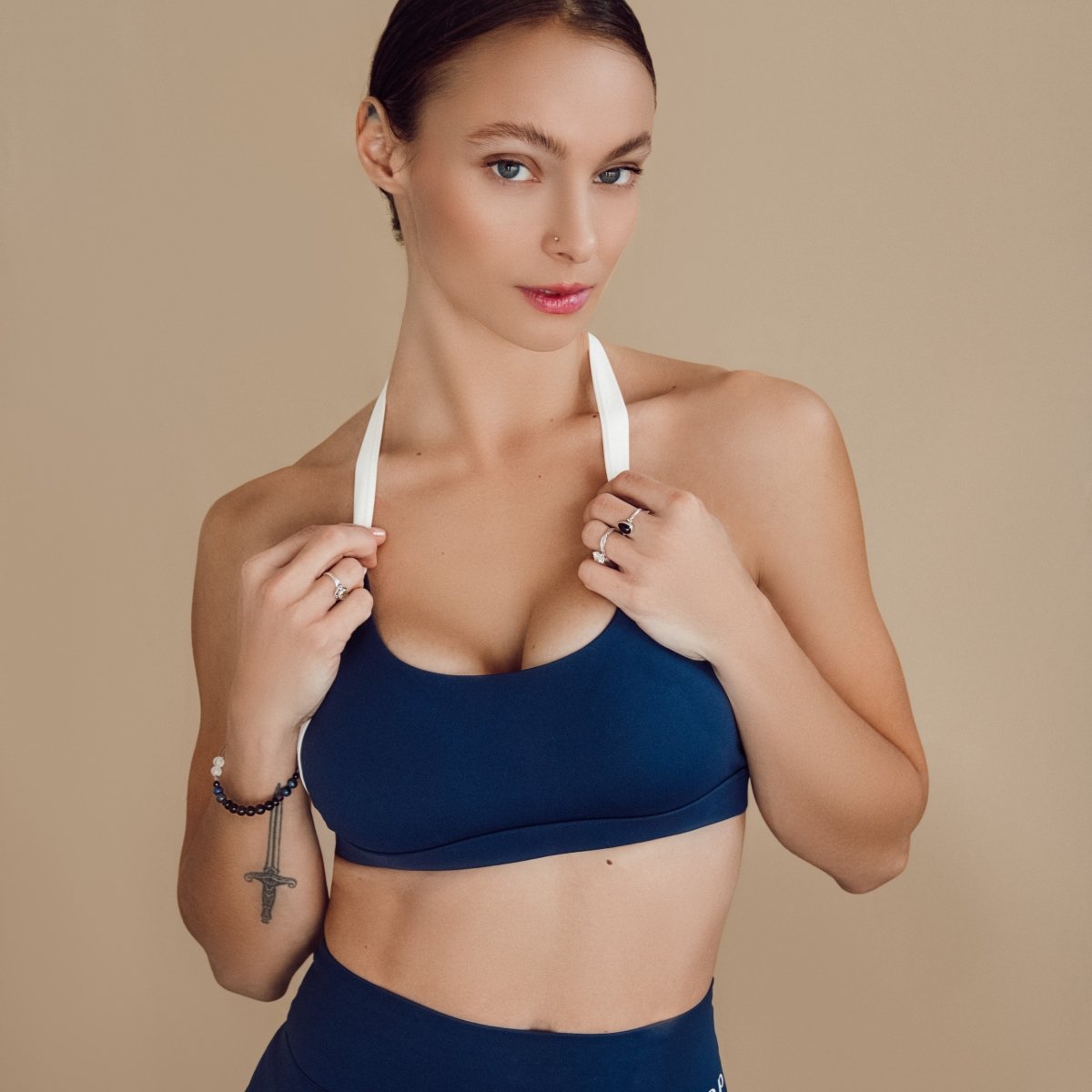 Woman wearing a blue sports bra and shorts on a beige background