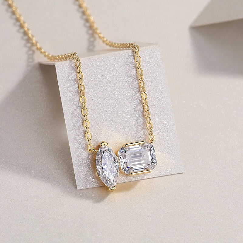 Gold necklace with two diamond pendants on a light background