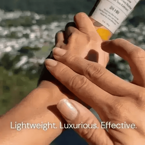 Person applying sunscreen to another person's hand with a scenic background